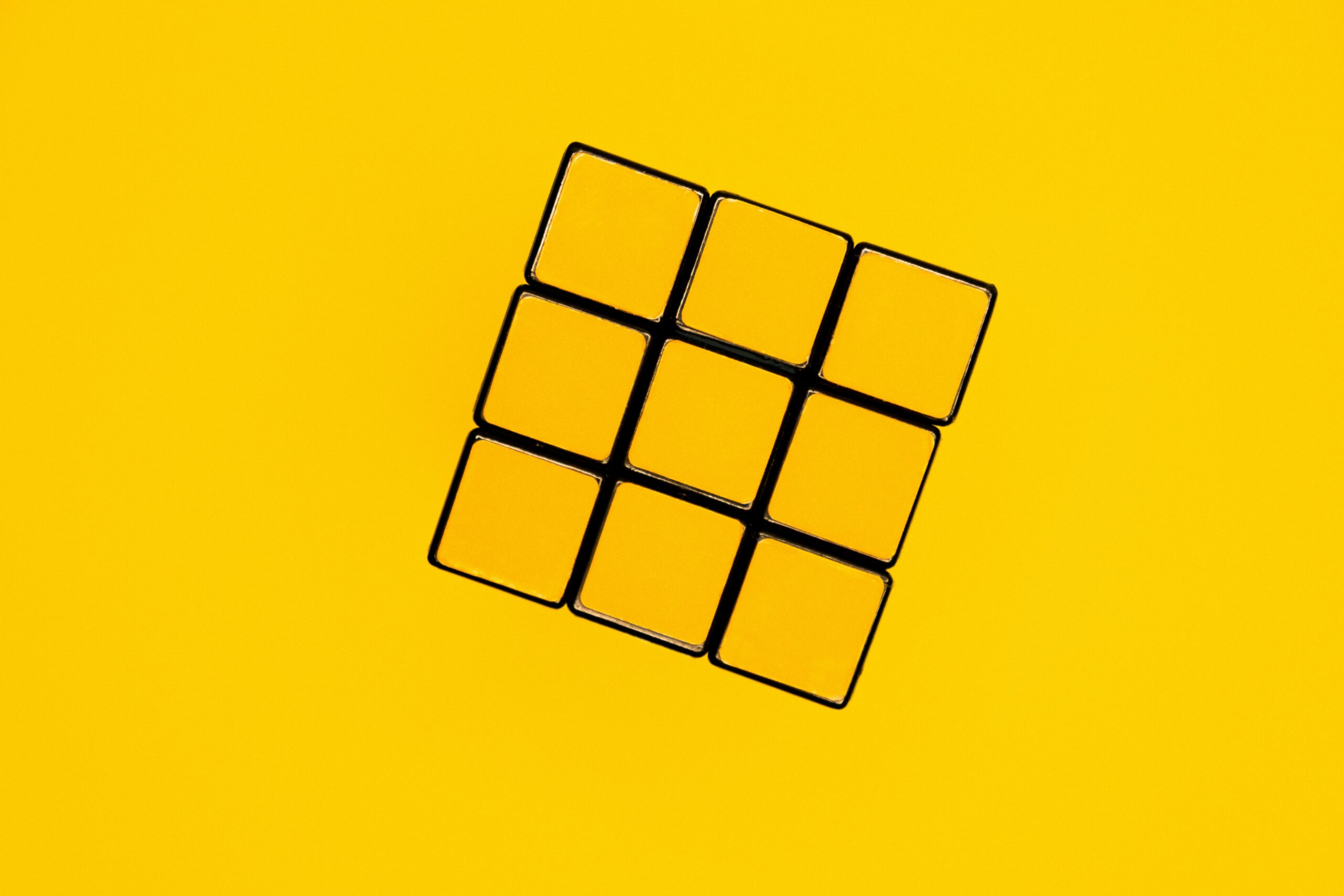 Gele Rubik's kubus op gele achtergrond.